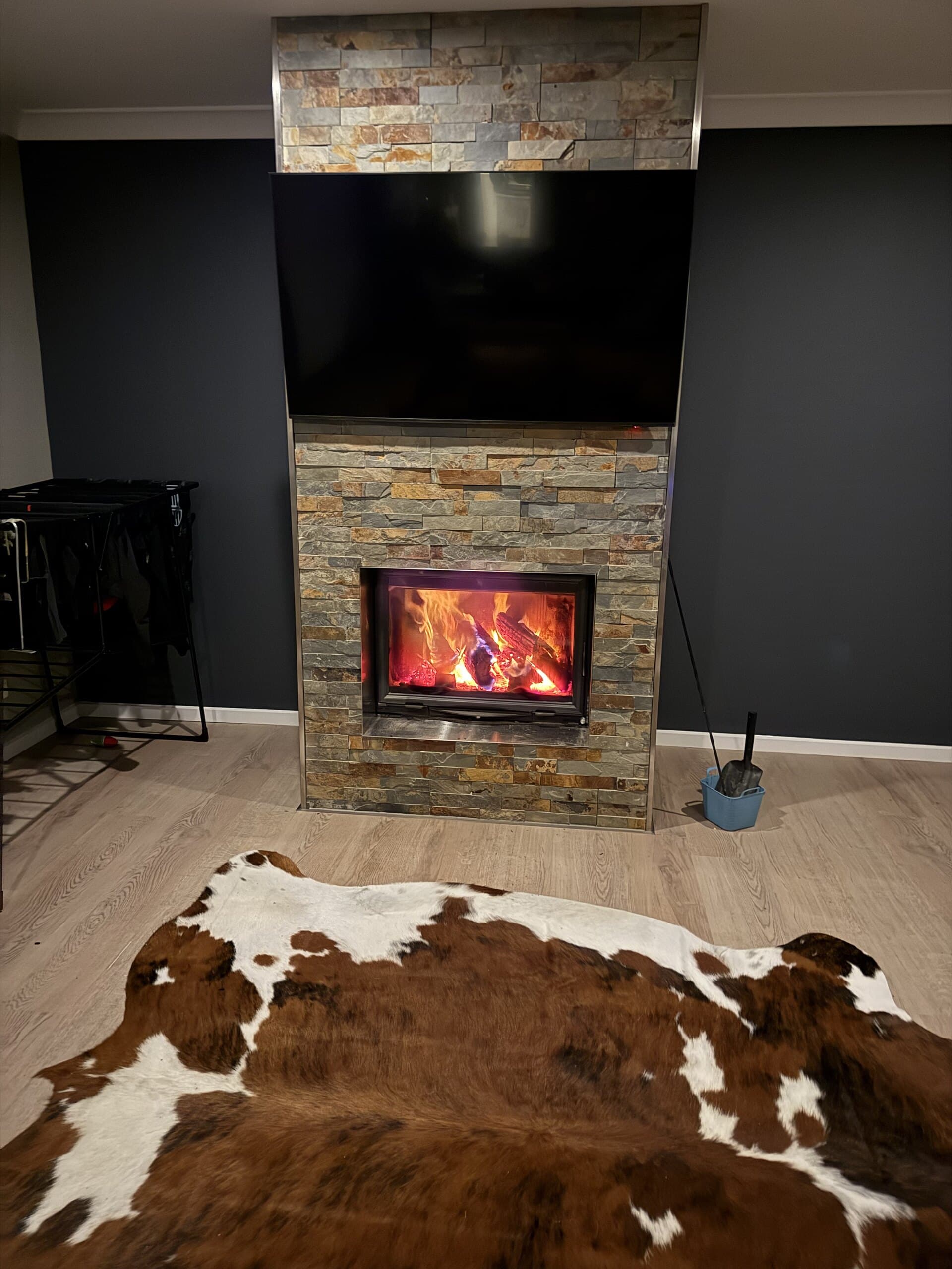 Indoor fireplace beneath a television with a cowhide rug