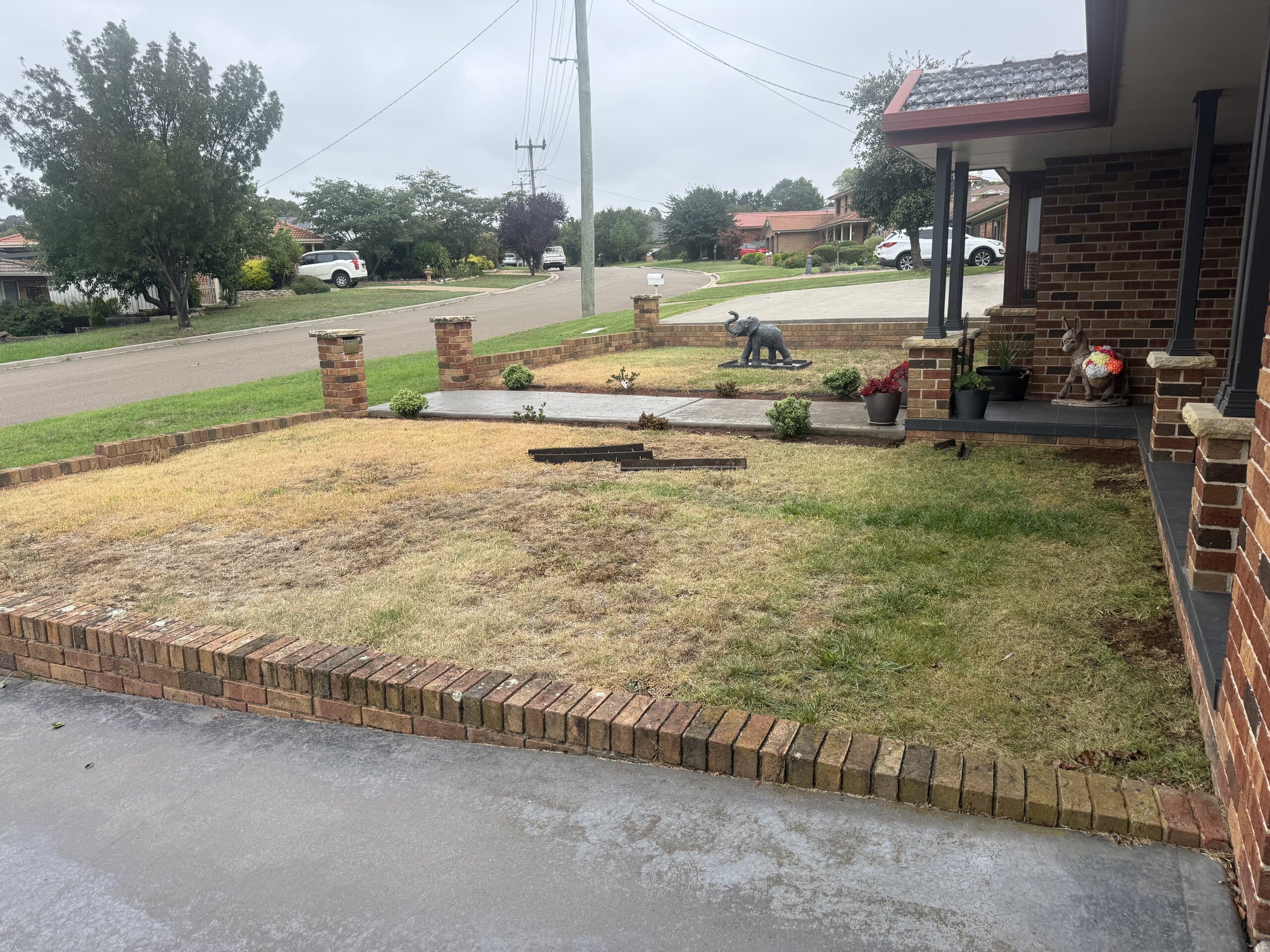 Dry front lawn beside a driveway and brick edging